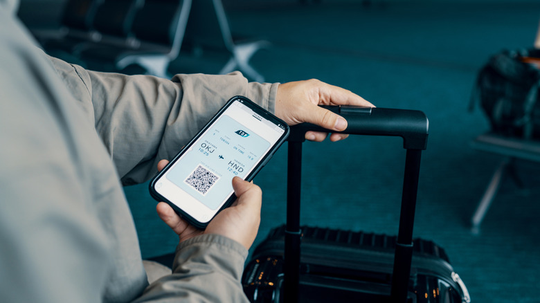 A person holding a smartphone with a boarding pass on the display