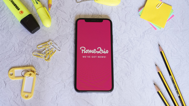 Rome2Rio logo on an iPhone surrounded with yellow stationery