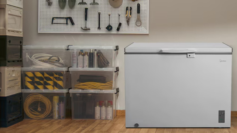A white cooler stands besides a shelf of work tools and two stacks of boxes filled with maintenance supplies.