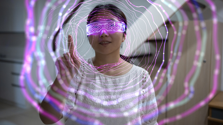 Person wearing futuristic AR glasses interacting with a holographic interface.