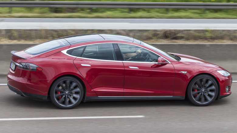 Red Tesla Model S driving on a road
