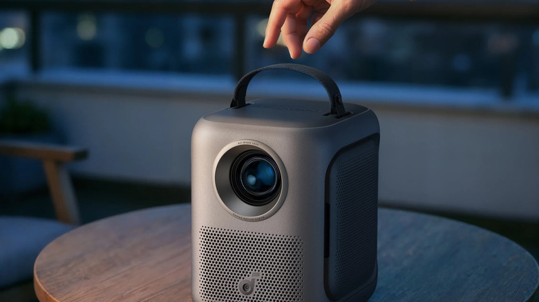 Hand grabbing soundcore Nebula P1i on table