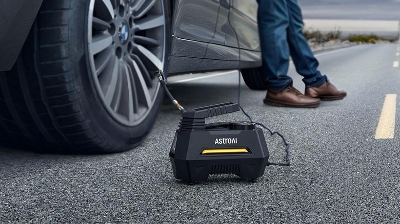 A person using AstroAI Tire Inflator to inflate their car tire