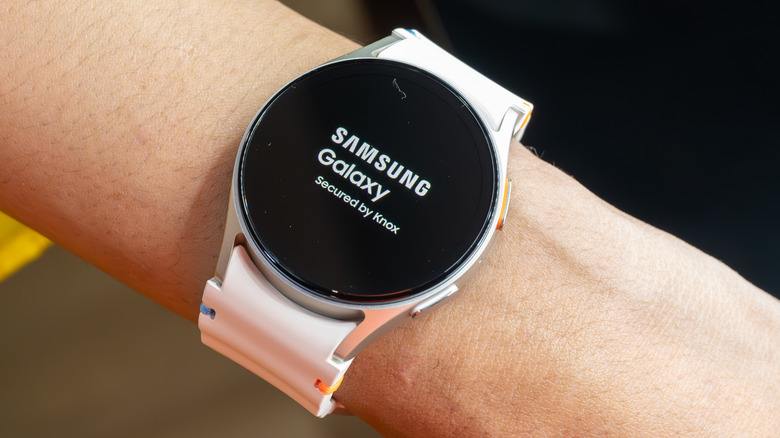 An arm with a Samsung Galaxy Watch 7 with a white band on the wrist.