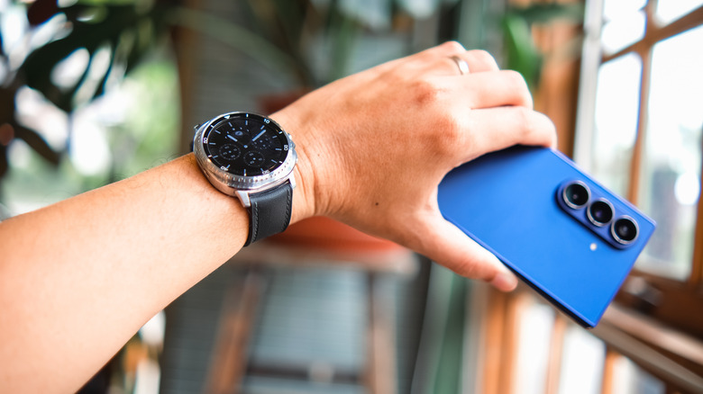An arm wearing the Samsung Galaxy Watch 8 and holding a Galaxy phone.