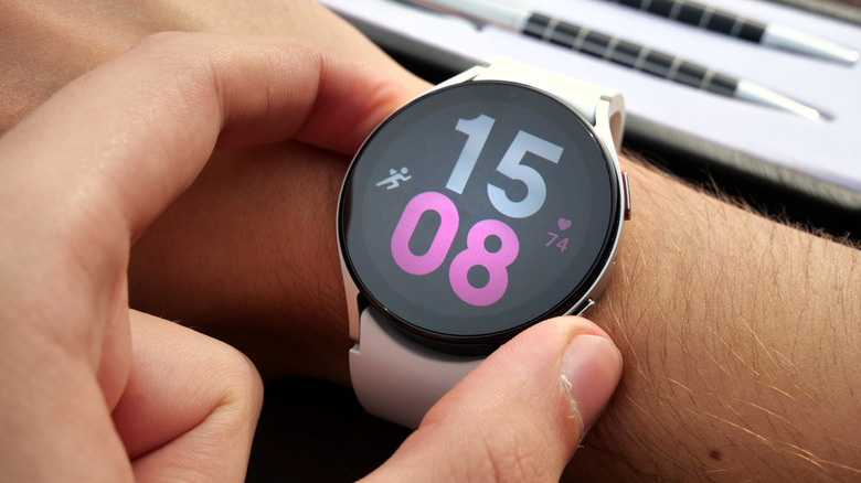 Two fingers pressing the side buttons on a Samsung Galaxy Watch 5.
