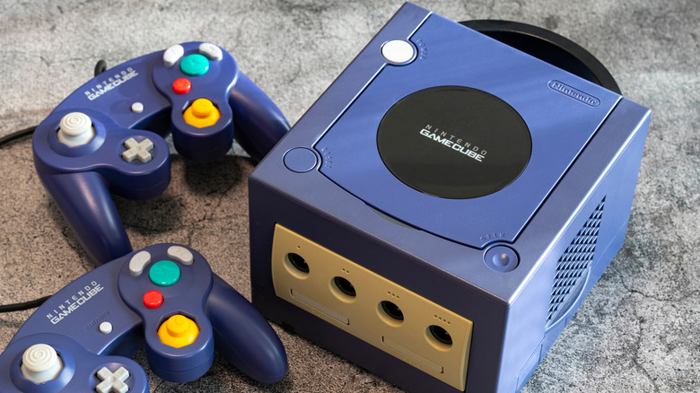 Nintendo GameCube console next to two controllers on a surface