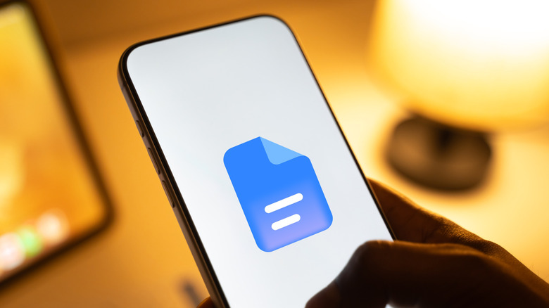 person pulling up google docs, google docs logo on smartphone display and white background