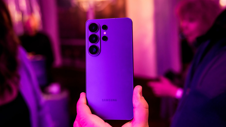 person holding up samsung smartphone, back of phone pointed to viewer