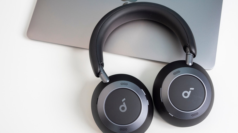 A pair of Anker Soundcore headphones placed on a closed MacBook.