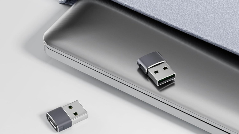 Two USB adapters sitting on top of a laptop.