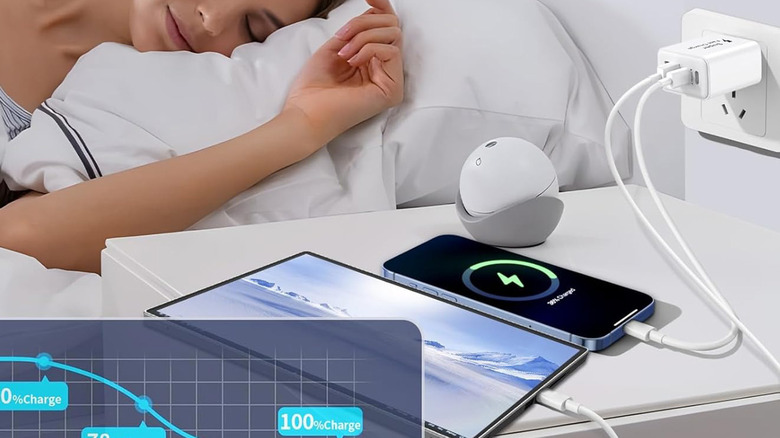 A woman sleeping with a charging block by the nightstand plugged in charging various devices.
