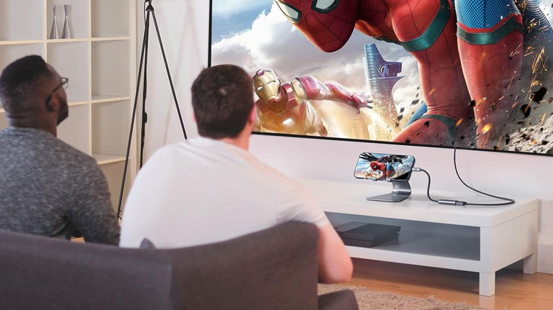 Two guys watching a movie with a phone plugged into the TV.
