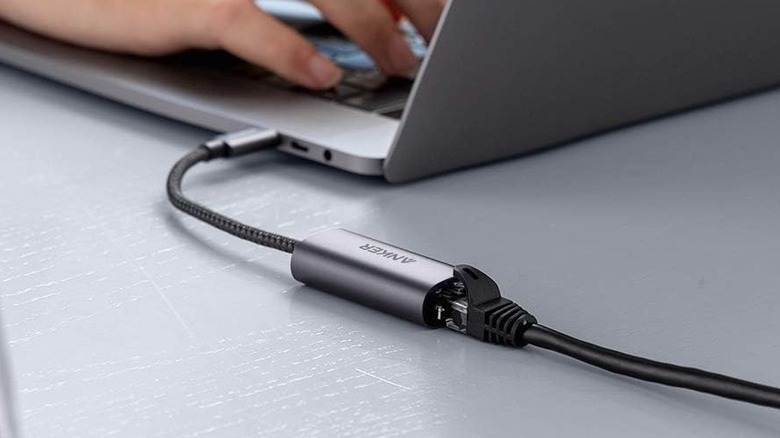 An Ethernet adapter plugged into a laptop's USB-C port and an Ethernet cable