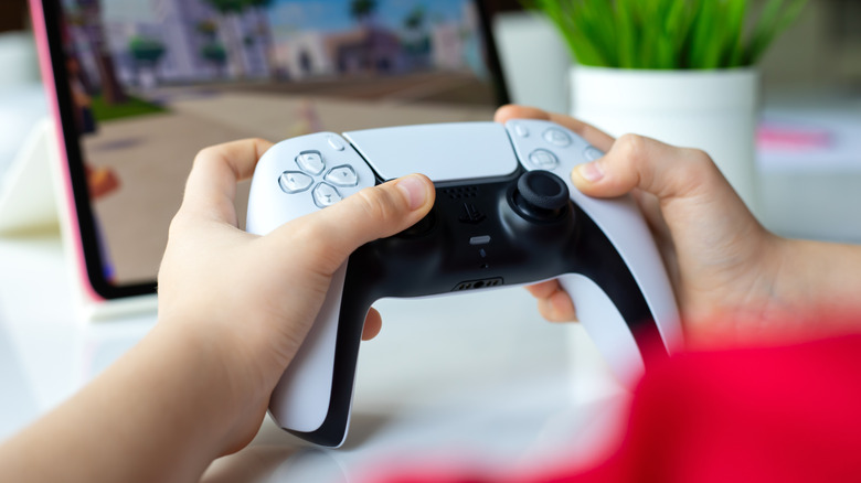 Close up of someone holding a PS5 controller to play a game on an iPad