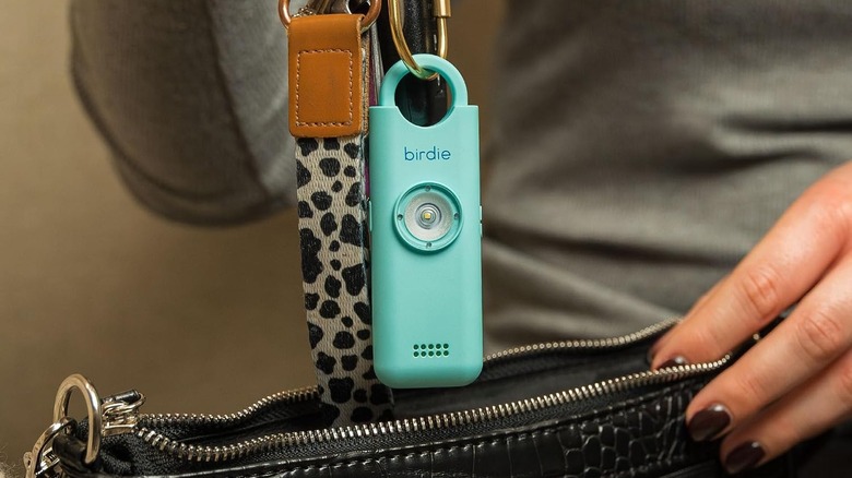 A blue She's Birdie 3.0 Personal Safety Alarm attached to a handbag.