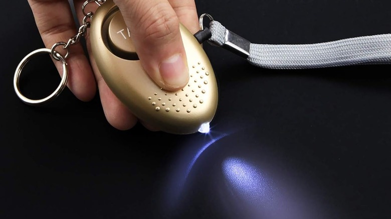 A person operating the built-in flashlight of the Taiker Self Defense Keychain.
