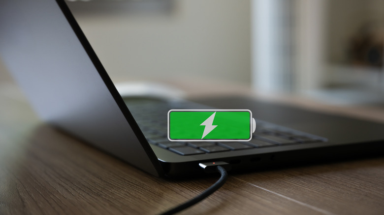 Laptop charging with a battery icon overlay showing full battery life.