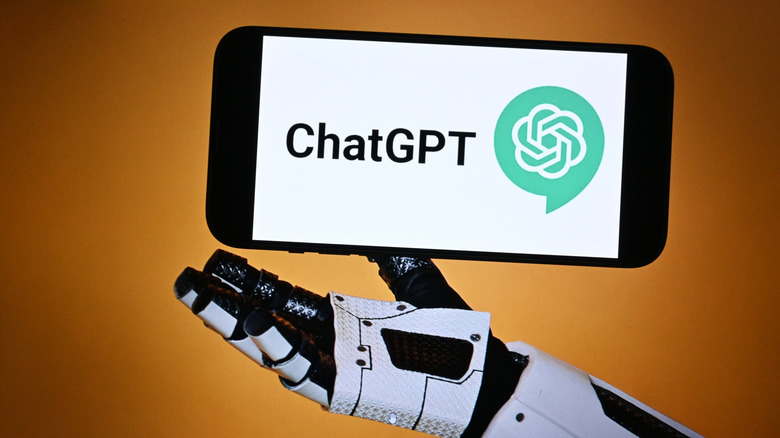 A smartphone with the ChatGPT logo on the display floating above a robot's hand
