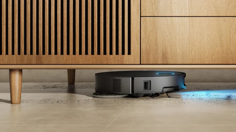 The Dreame X60 Max Ultra Complete robot vacuum cleaner cleaning dirt under a dresser