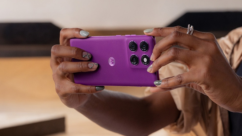Person holding a purple Motorola Edge 60 Pro horizontally with the rear cameras facing forward.