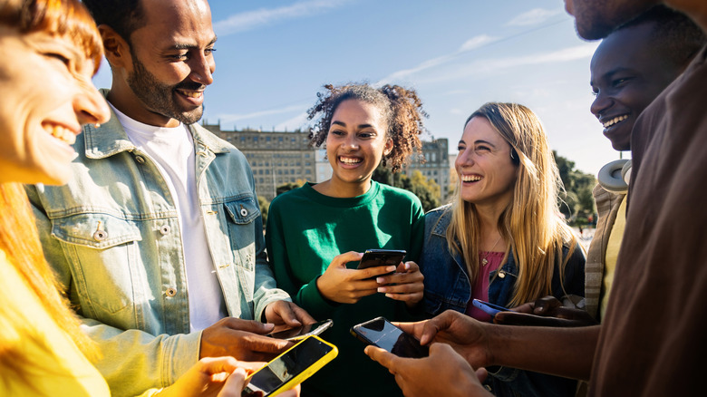 Gen Z smiling in a circle holding phones