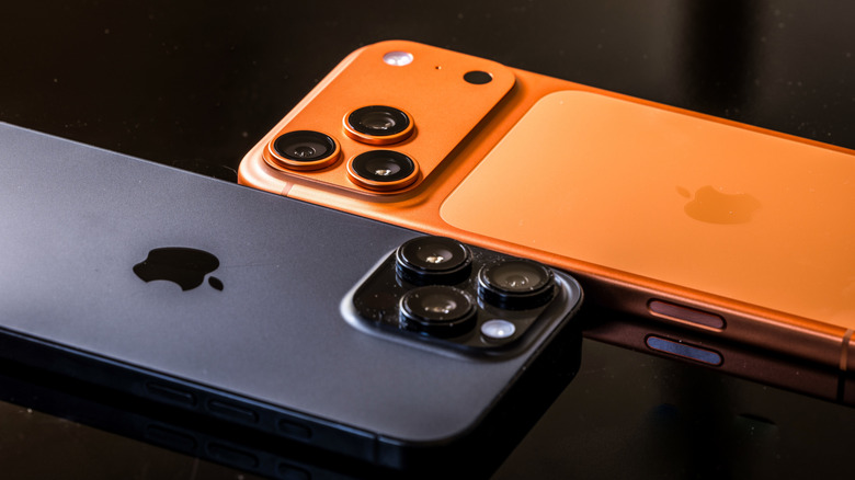 An orange and a black iPhone sitting next to each other against a black background