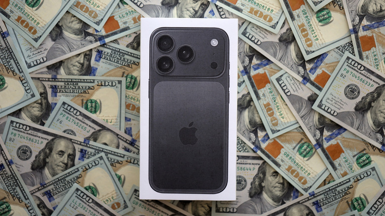 An iPhone box sits atop a pile of crisp hundred-dollar bills