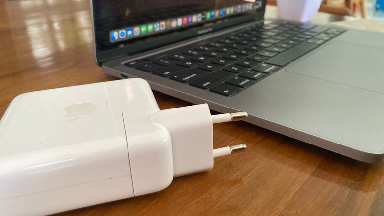 A MacBook with a charging brick on a flat surface