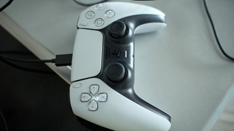 A DualSense controller plugged in while sitting on the table