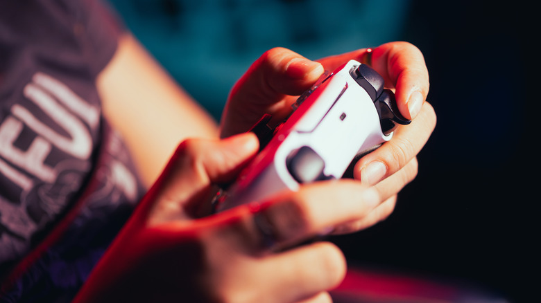 A person holding a DualSense controller with their fingers on the triggers