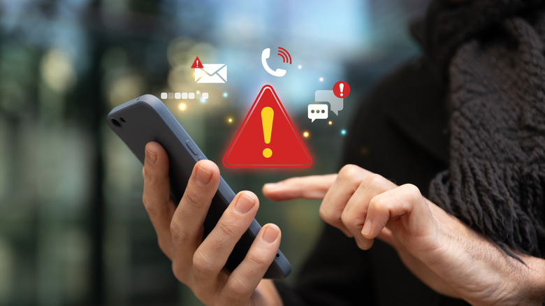 A person holding a phone with a warning sign next to app alerts