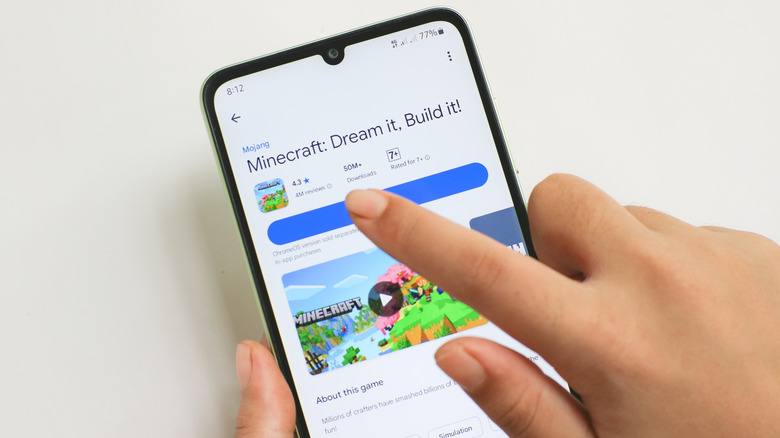 A person tapping the download button on the Minecraft app in the Google Play Store