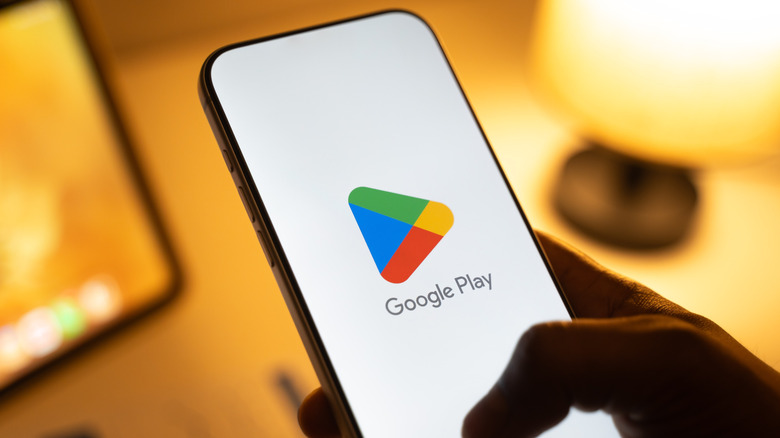 Aperson holding a smartphone showing the Google Play logo on the screen