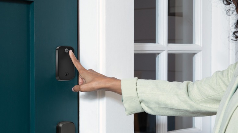 An individual has their hand hovering over the touch portion of the Yale Assure Lock 2 Touch Deadbolt