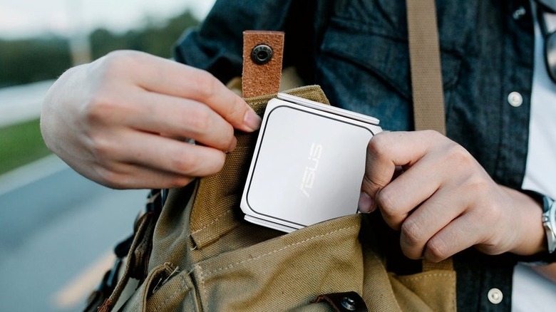 Close-up of a person putting the Asus RT-BE58 Go travel router in a bag
