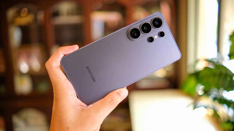 Samsung smartphone held up by a person, blurred office background