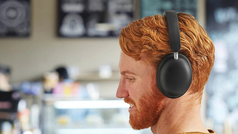 A red-headed man wears a pair of Onn Wireless Over-Ear Headphones in a cafe setting.