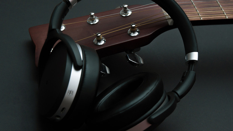 Modern headphones and part of an acoustic guitar.