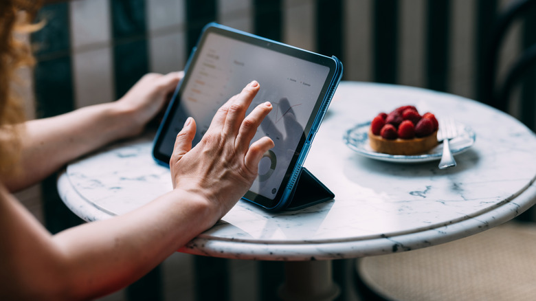 Person sitted at a table using a tablet