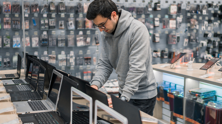 A person explores laptops in a store