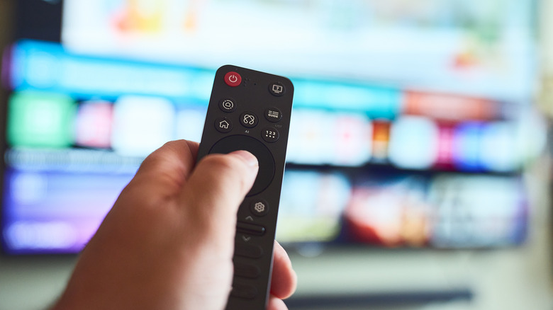 Person holding a smart TV remote, navigating the TV interface.
