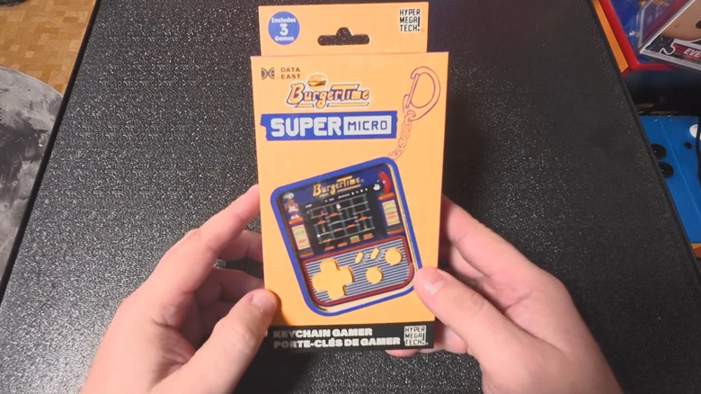 Man holding HyperMegaTech Super Micro BurgerTime keychain game console box