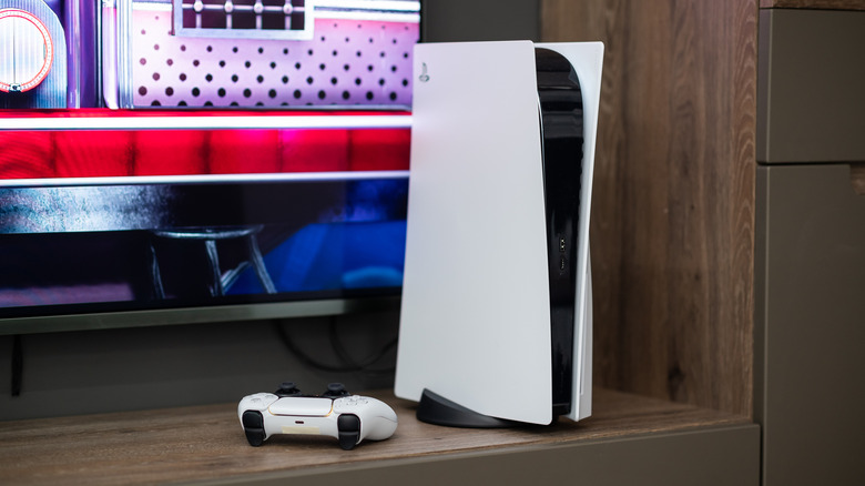 The Sony PlayStation 5 gaming console with a DualSense controller near a TV screen