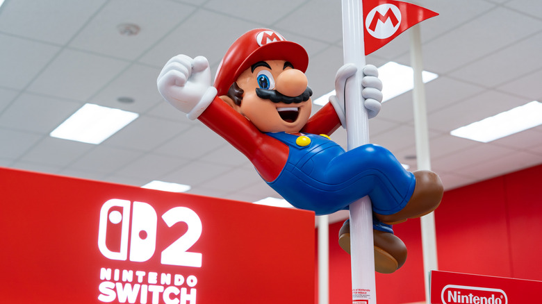 A Mario statue hanging on a pole with a Nintendo Switch 2 sign in the background