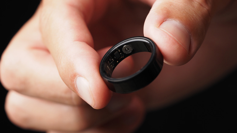 Close-up of a person's fingers holding a smart ring