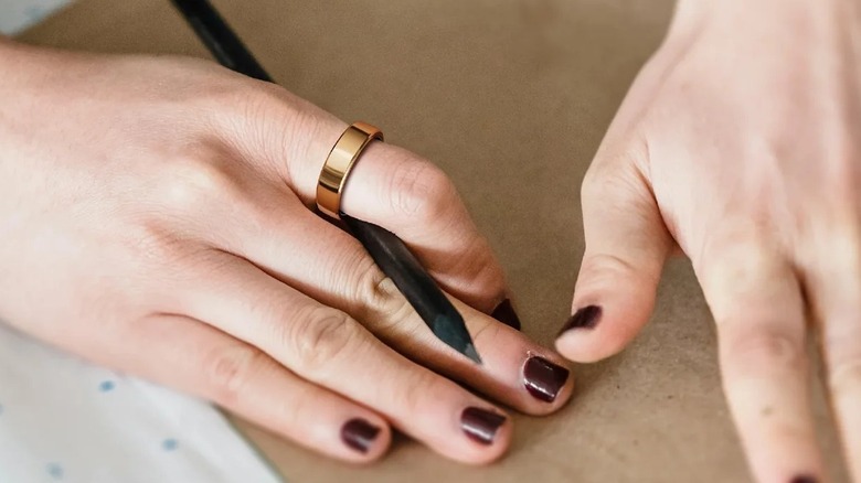 A person working with a pencil and paper while wearing the RingConn Gen 2 smart ring
