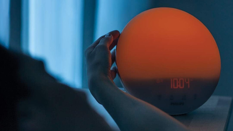Reaching for the Philips SmartSleep Wake-up Light on a bedside table