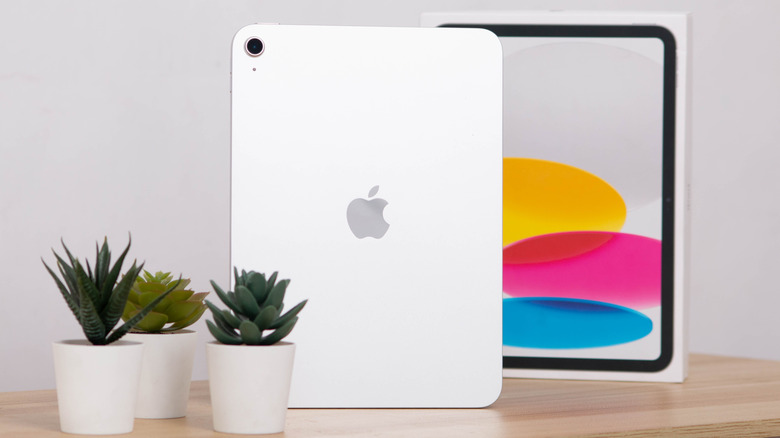 Rear view of the Apple iPad 11-inch (2025) standing upright on a desk with its box in the background.