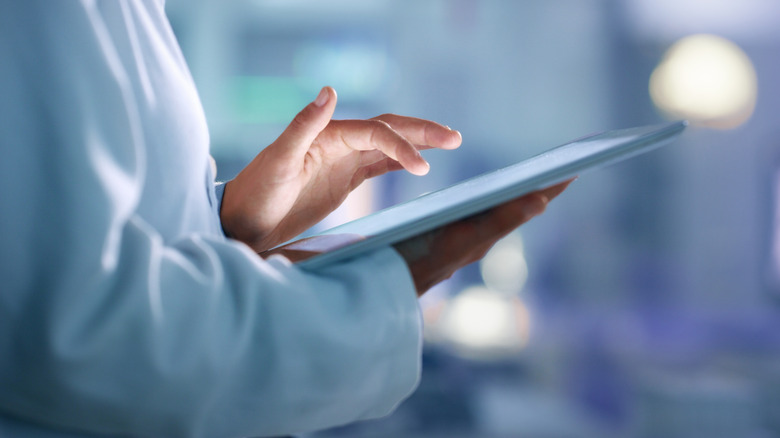 A person using a tablet with one hand.